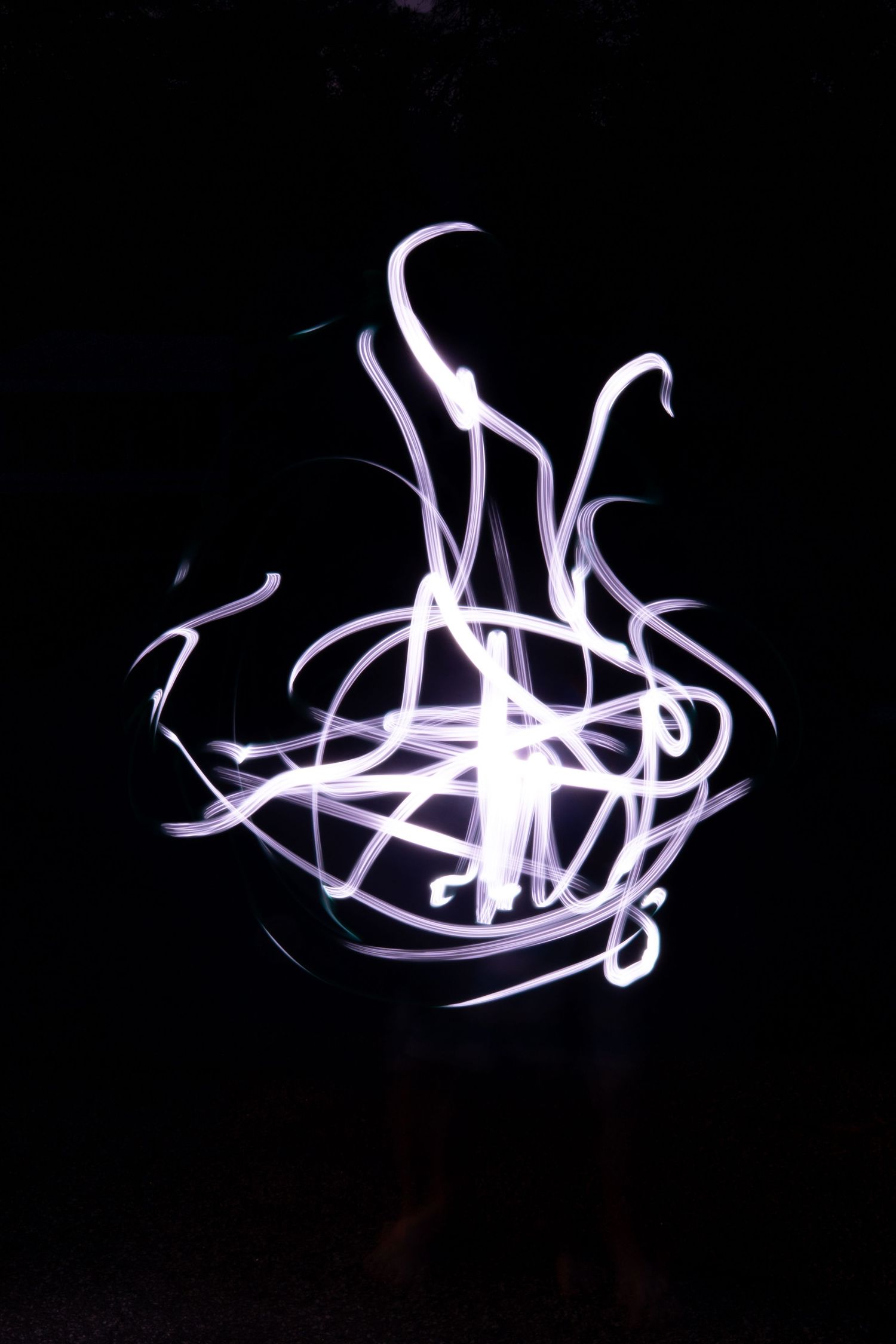 White light painting swirls forming a glowing vase shape against a black background in long exposure.