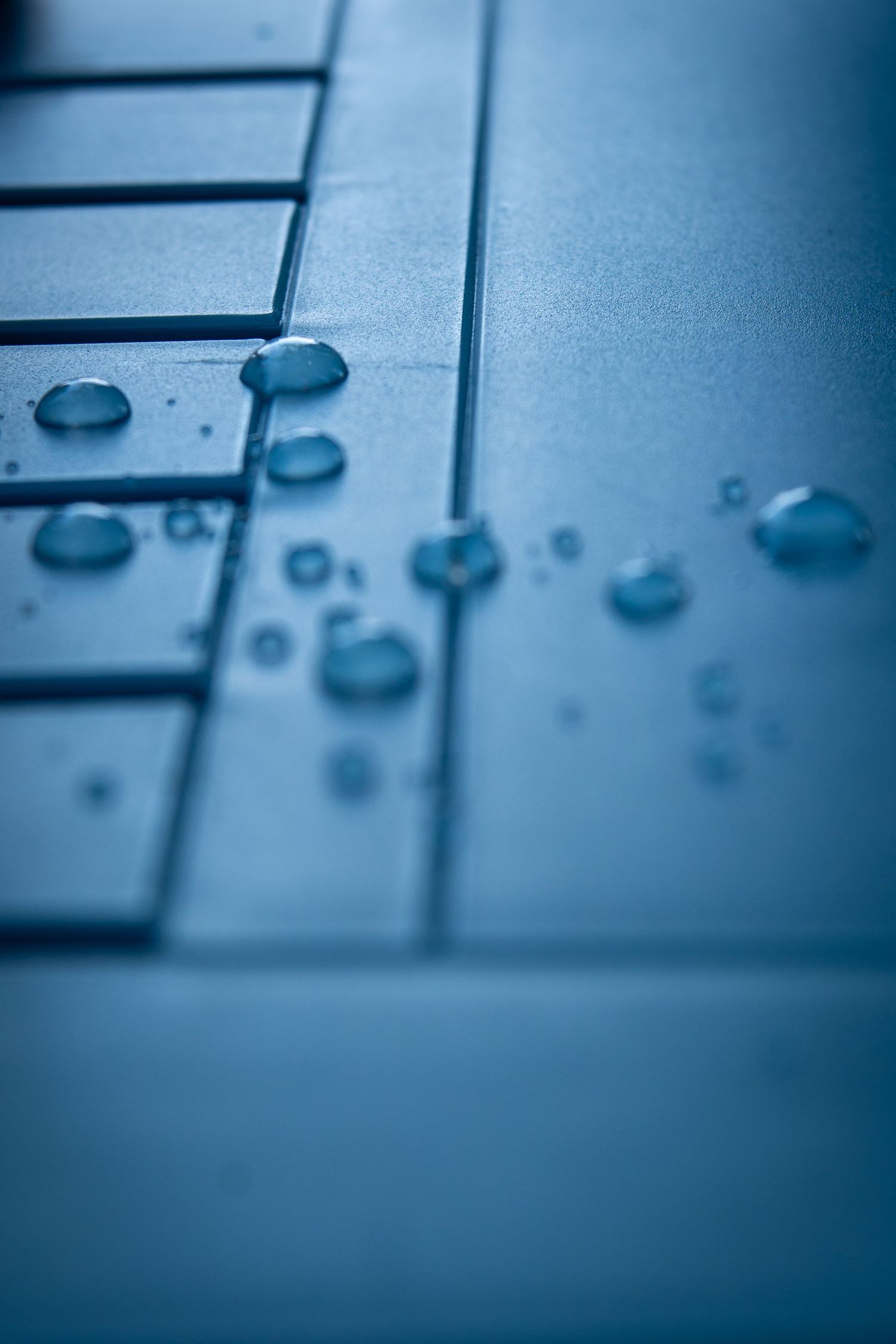 Close-up macro shot of computer keyboard keys in cool blue tones with shallow depth of field.