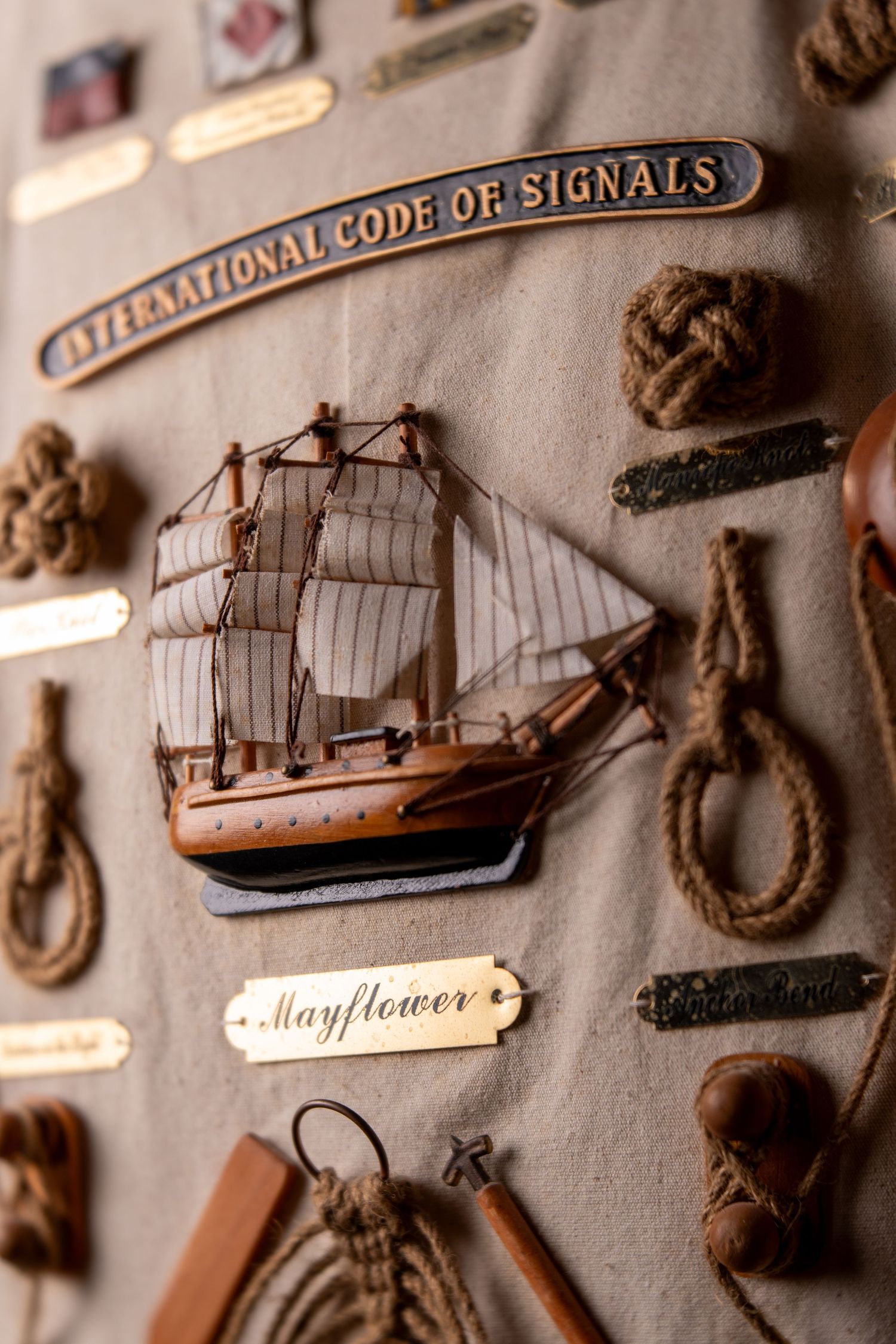 Mayflower ship model display board featuring nautical knots, rope samples, and International Code of Signals sign.