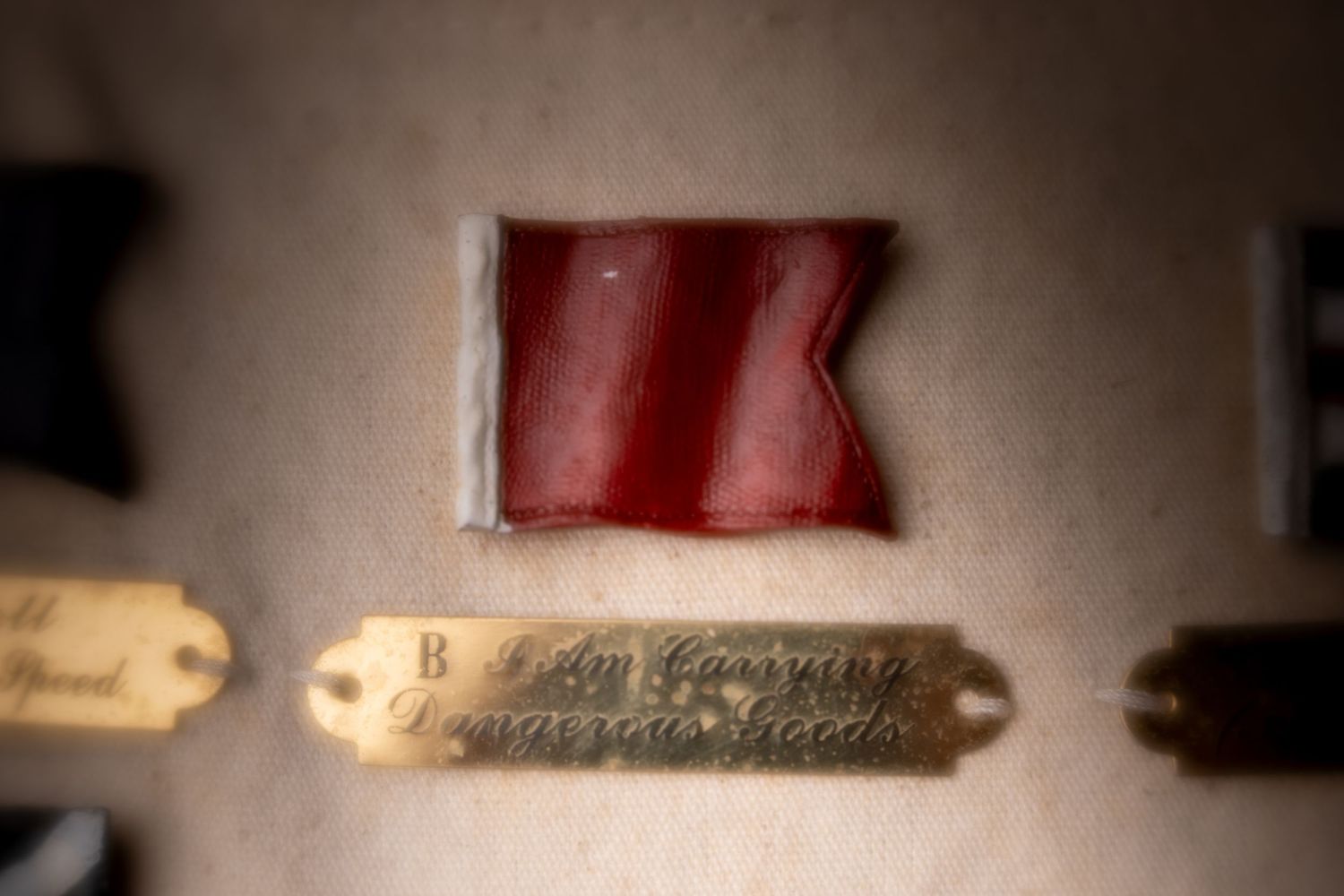 Close-up of a red wax seal fragment above a brass label plate marked Dangerous Goods on aged paper.