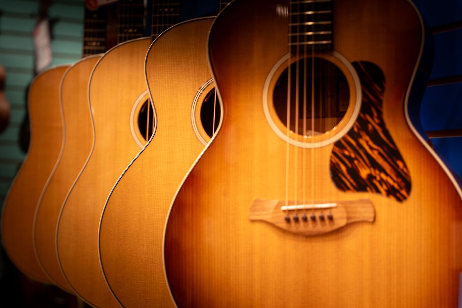 A row of acoustic guitars with sunburst finish displayed in a music store, showcasing their elegant curves and wood grain.