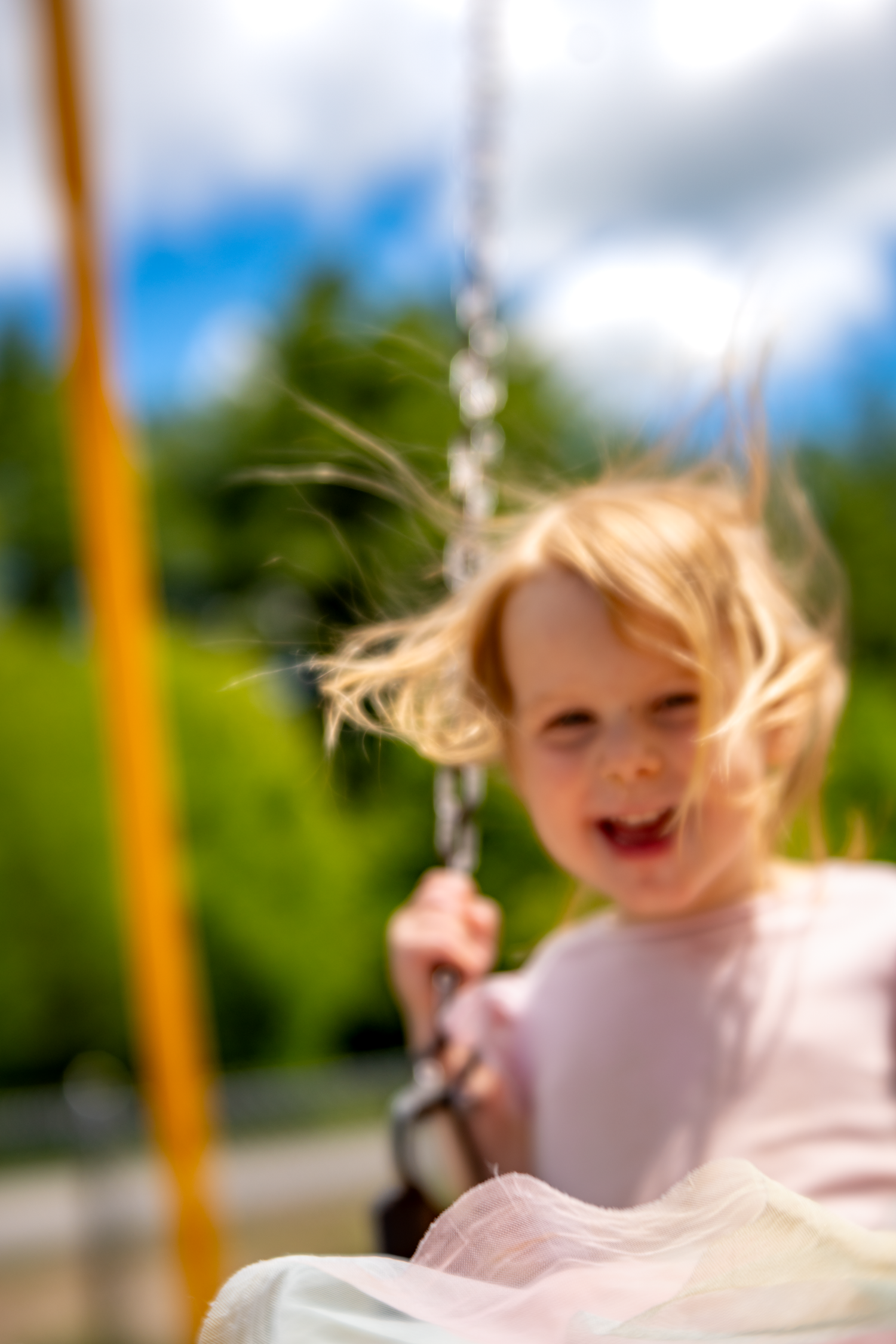 A sequence of motion shots shows a child with windblown hair swinging joyfully outdoors on a sunny day.