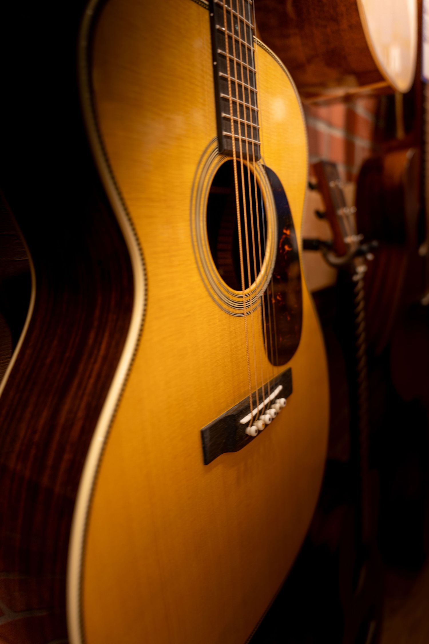 Close-up of a natural wood acoustic guitar with rosewood sides and decorative soundhole rosette detail.