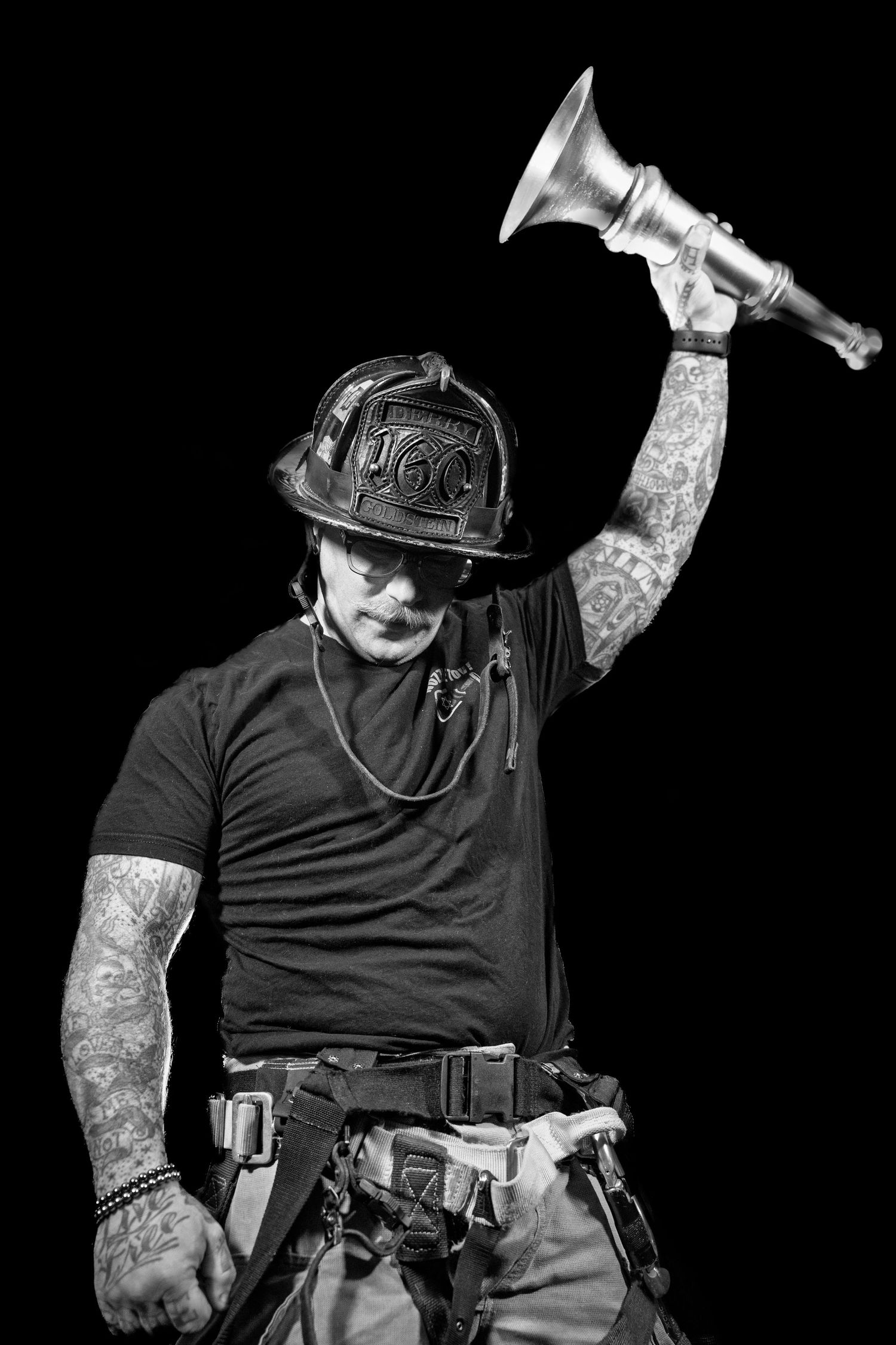 Black and white photo series showing firefighter in protective gear with helmet and tattoos in different action poses.
