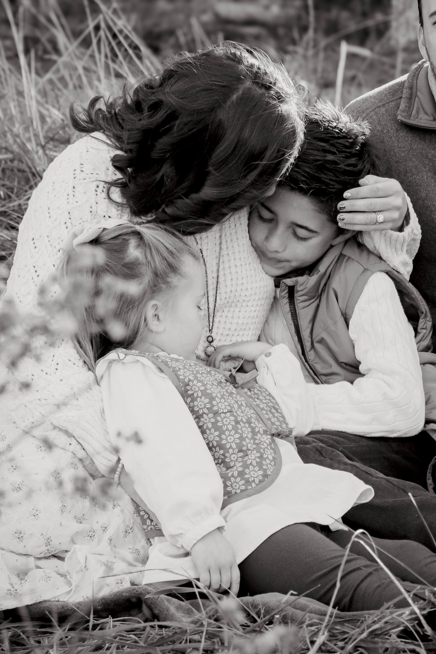 Lifestyle family session with three people taken outdoors in black and white photography style.