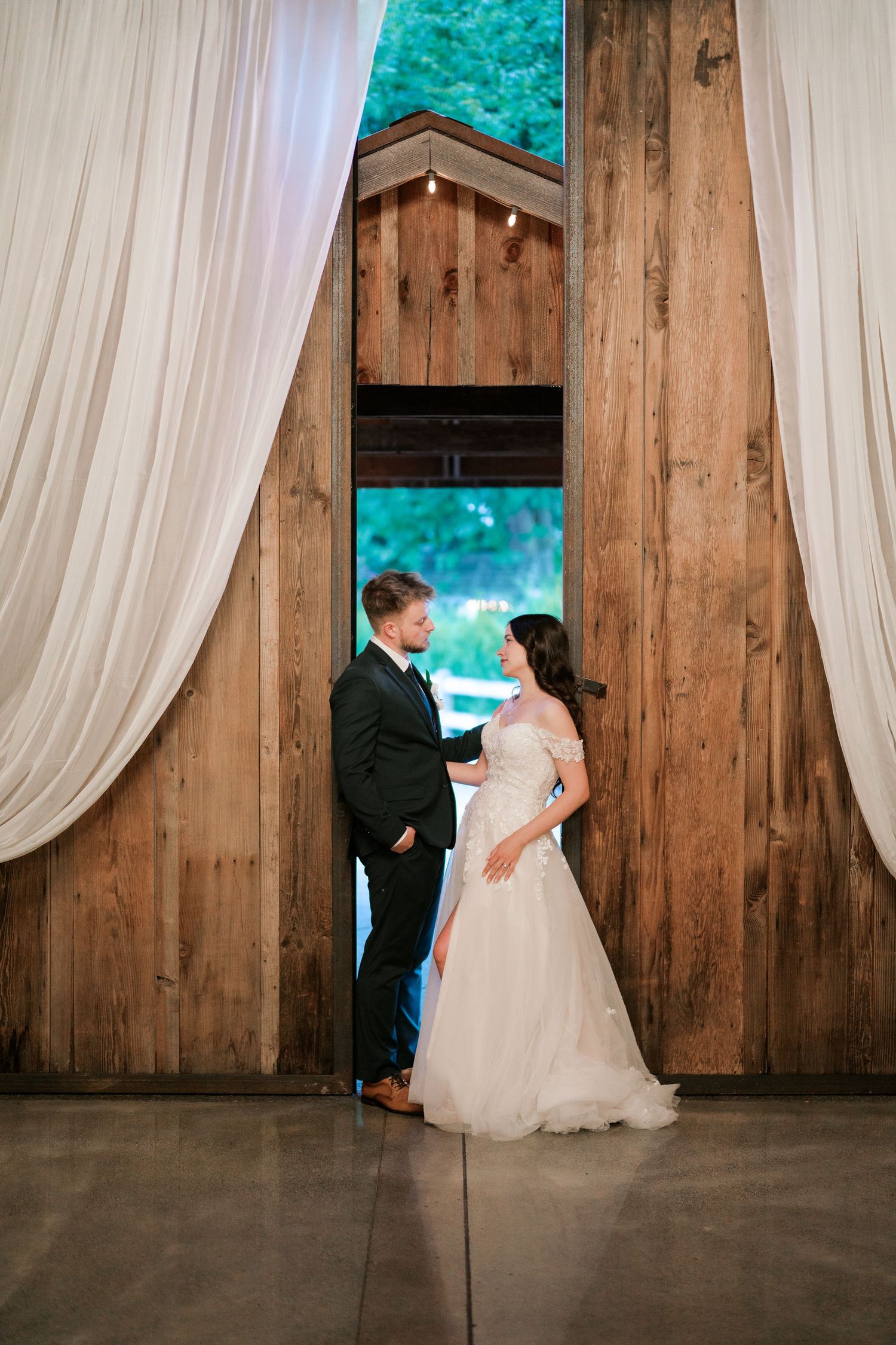 Bride and groom in the draped barn doorway at their Kelley Farm wedding, Bonney Lake