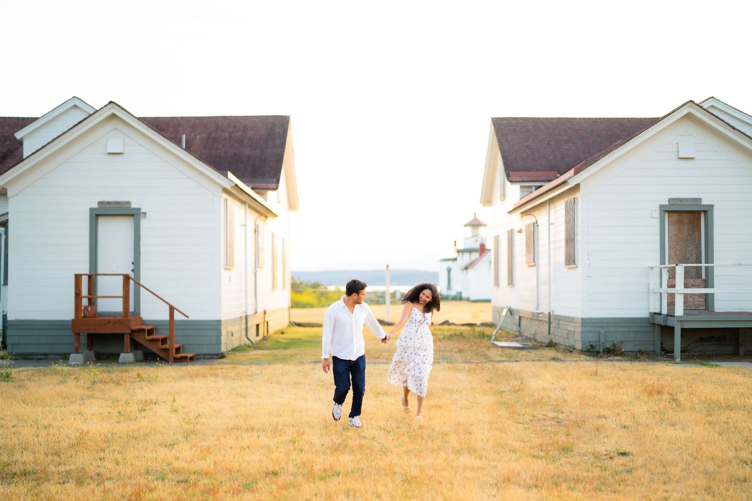 Walking between the white keeper's cottages by the lighthouse, West Point Lighthouse proposal photographer, Discovery Park