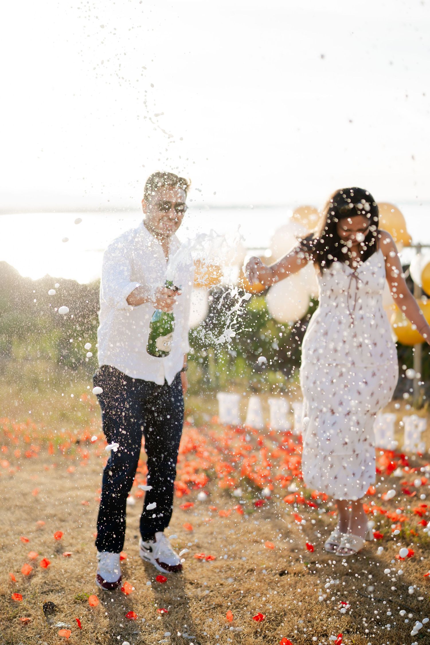 Champagne sprays over the petals right after she said yes, West Point Lighthouse proposal photographer, Seattle