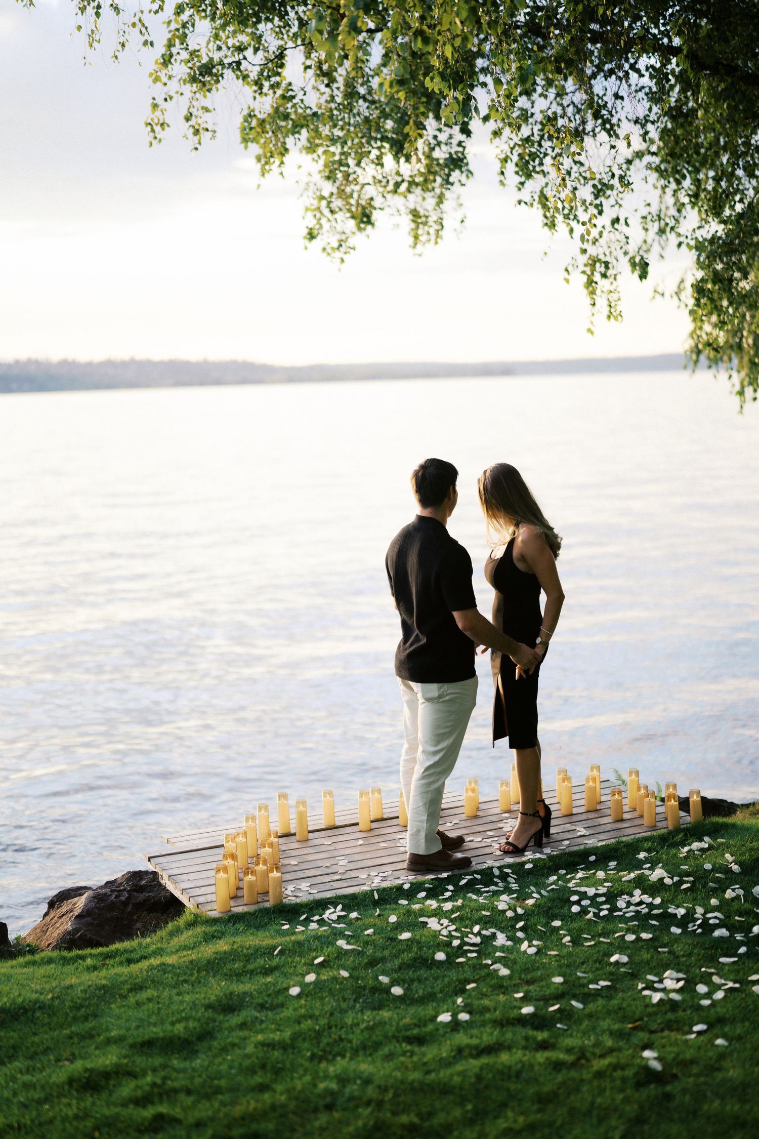 Couple facing each other at the water edge with candles on the dock, Carillon Point, Kirkland