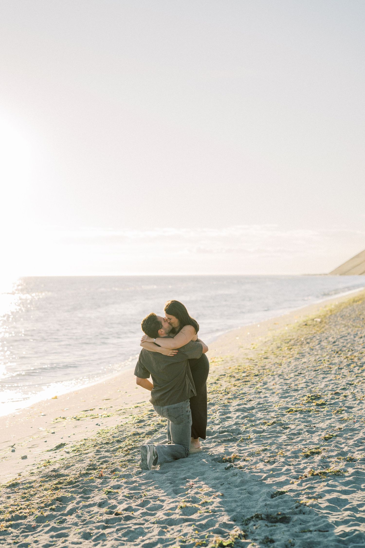 Holding each other on the sand as the sun goes down over the water, Whidbey Island proposal photographer, Freeland WA