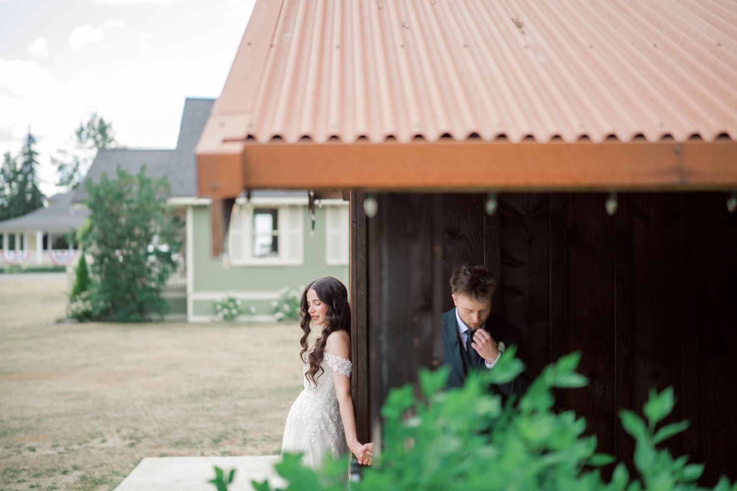 Bride and groom holding hands by the barn and farmhouse at The Kelley Farm, Bonney Lake