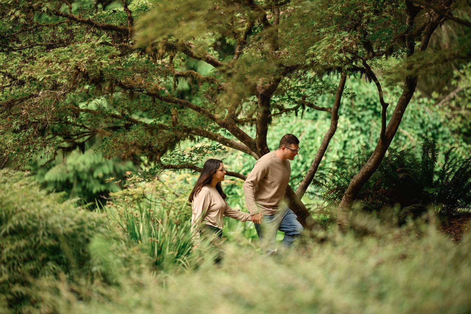 Couple walking hand in hand through tall ferns at the Arboretum, Washington Park Arboretum proposal photographer, Seattle