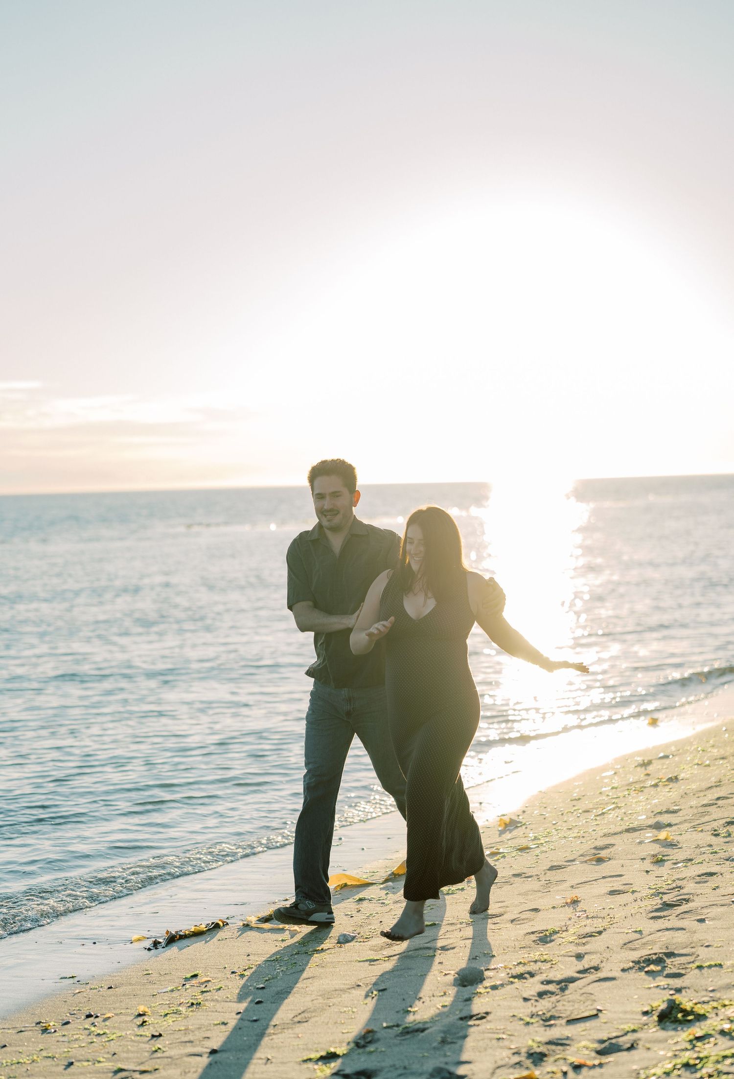 Couple on the shoreline with the sun low over the water, Whidbey Island proposal photographer, Freeland