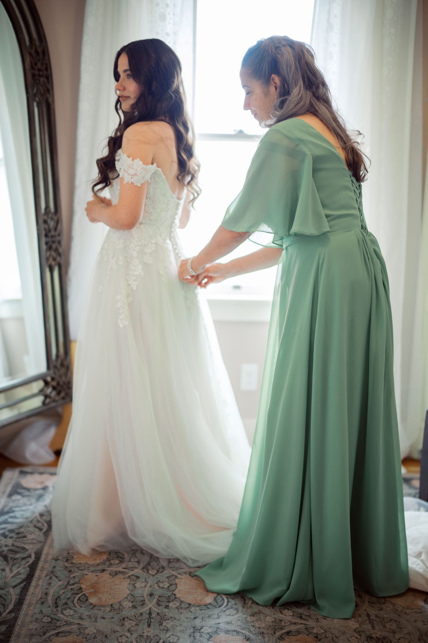 A bridesmaid fastens the bride dress at The Kelley Farm in Bonney Lake