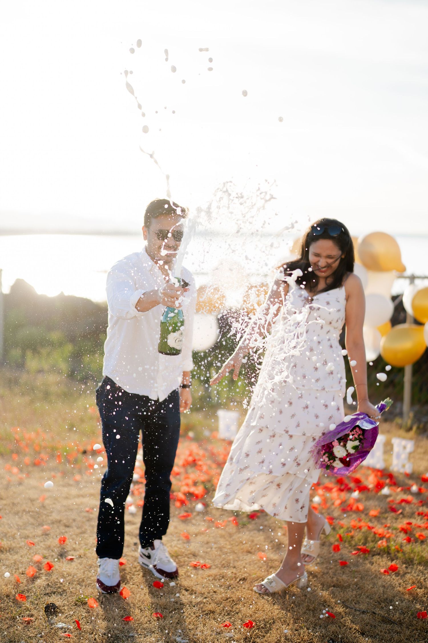 Laughing through the champagne in the meadow above the beach, proposal photographer at West Point Lighthouse, Seattle