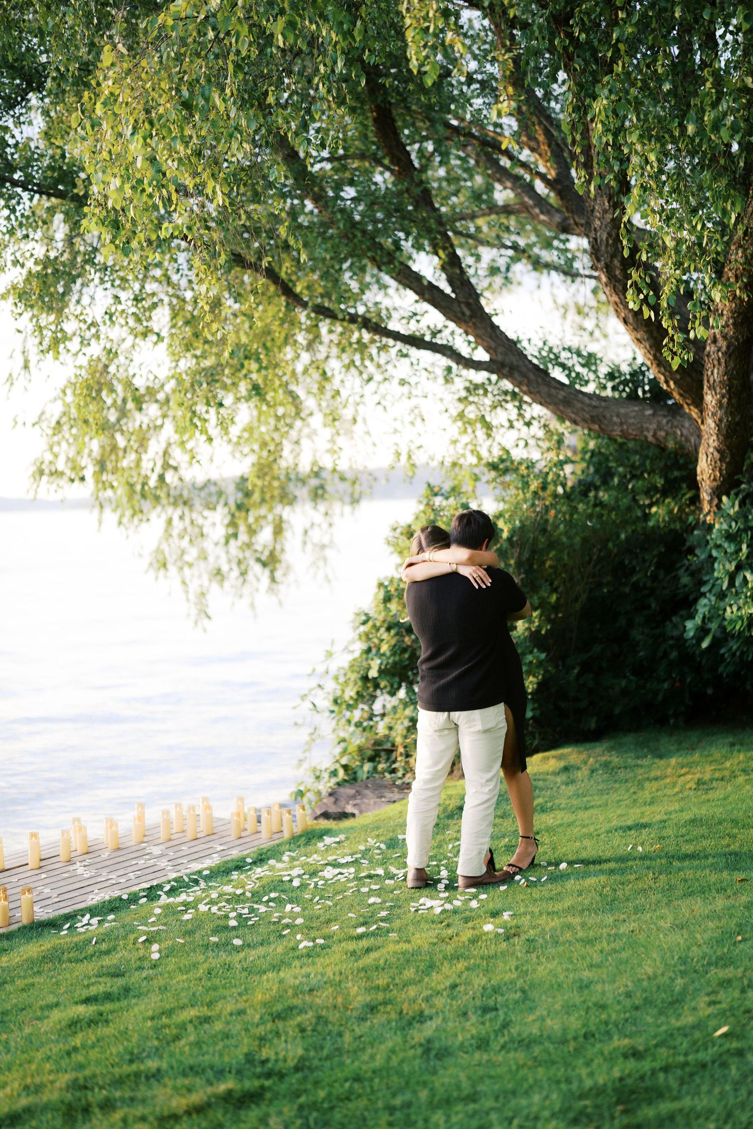 Couple holding each other on the grass after the proposal at Carillon Point, Kirkland