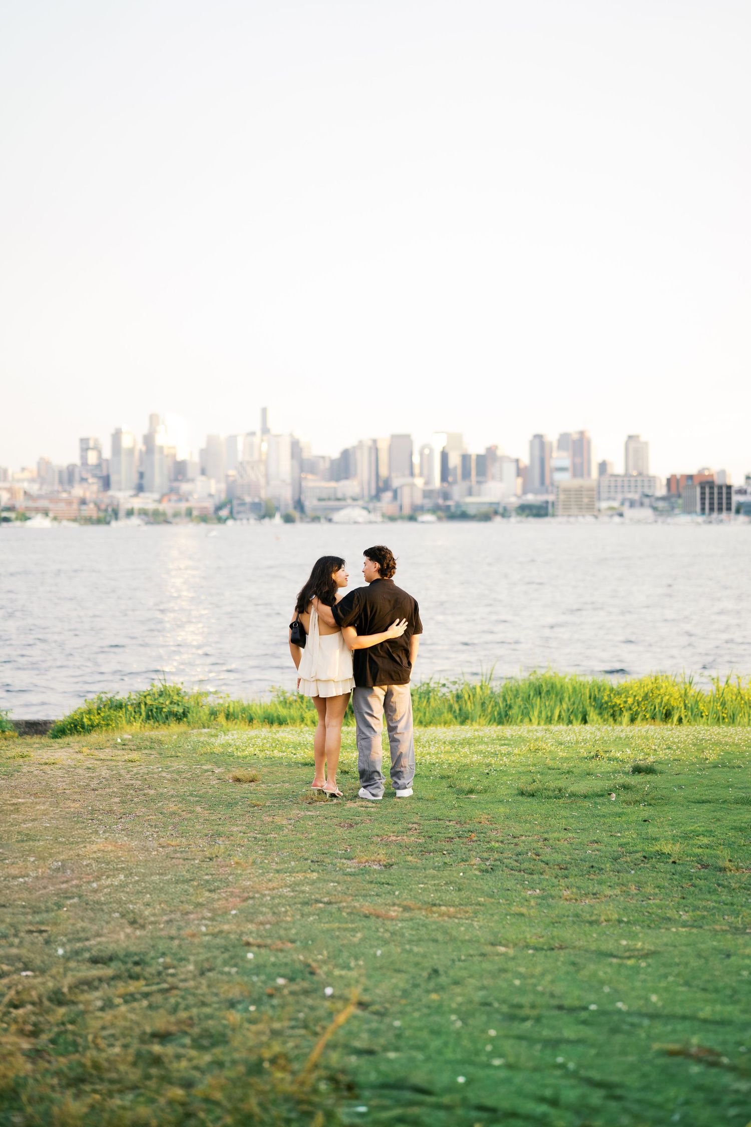 Couple embracing on the grass at Gas Works Park with the Seattle skyline across Lake Union, Gas Works Park proposal photographer