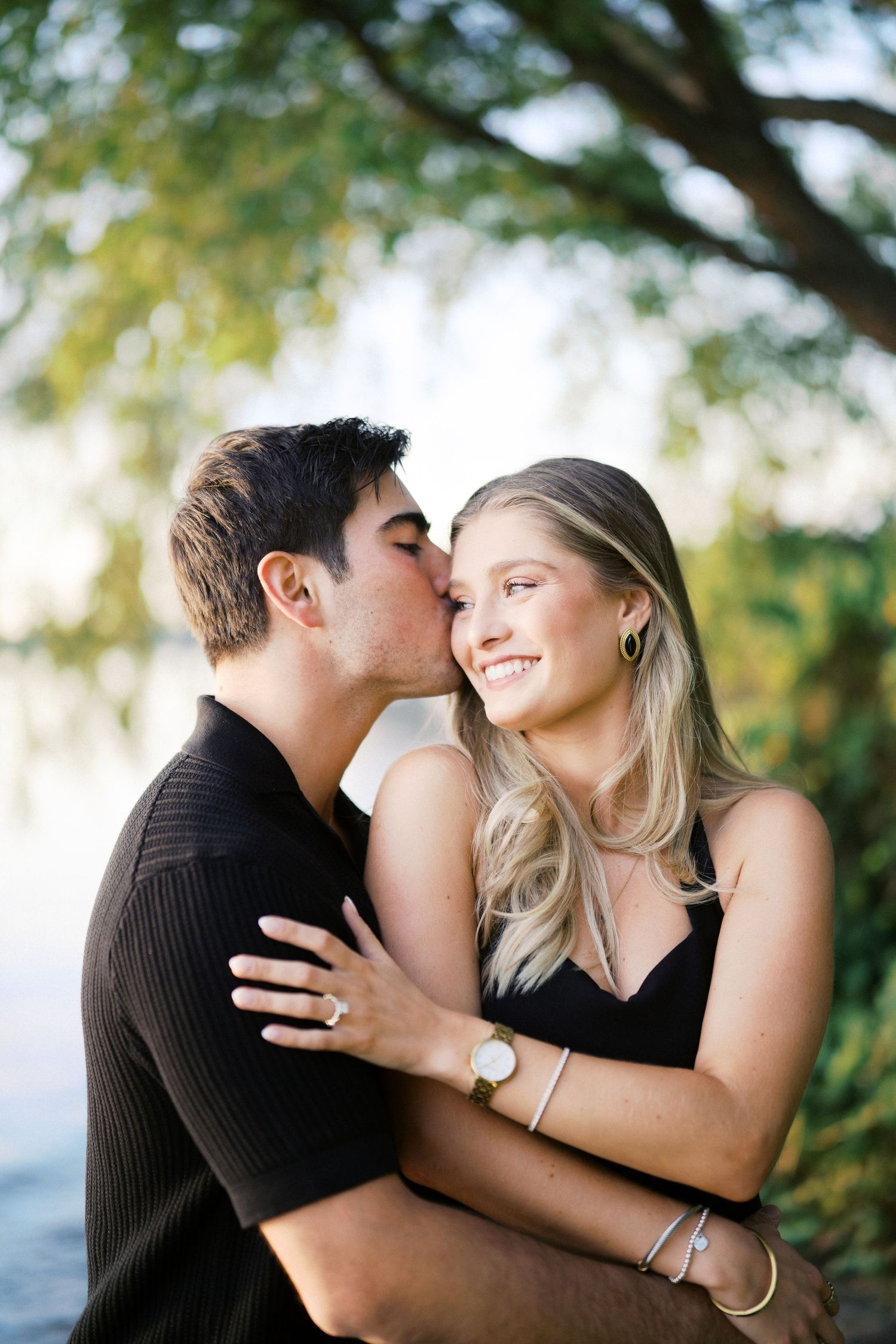 He kisses her temple on the lawn at Carillon Point, Kirkland proposal photographer