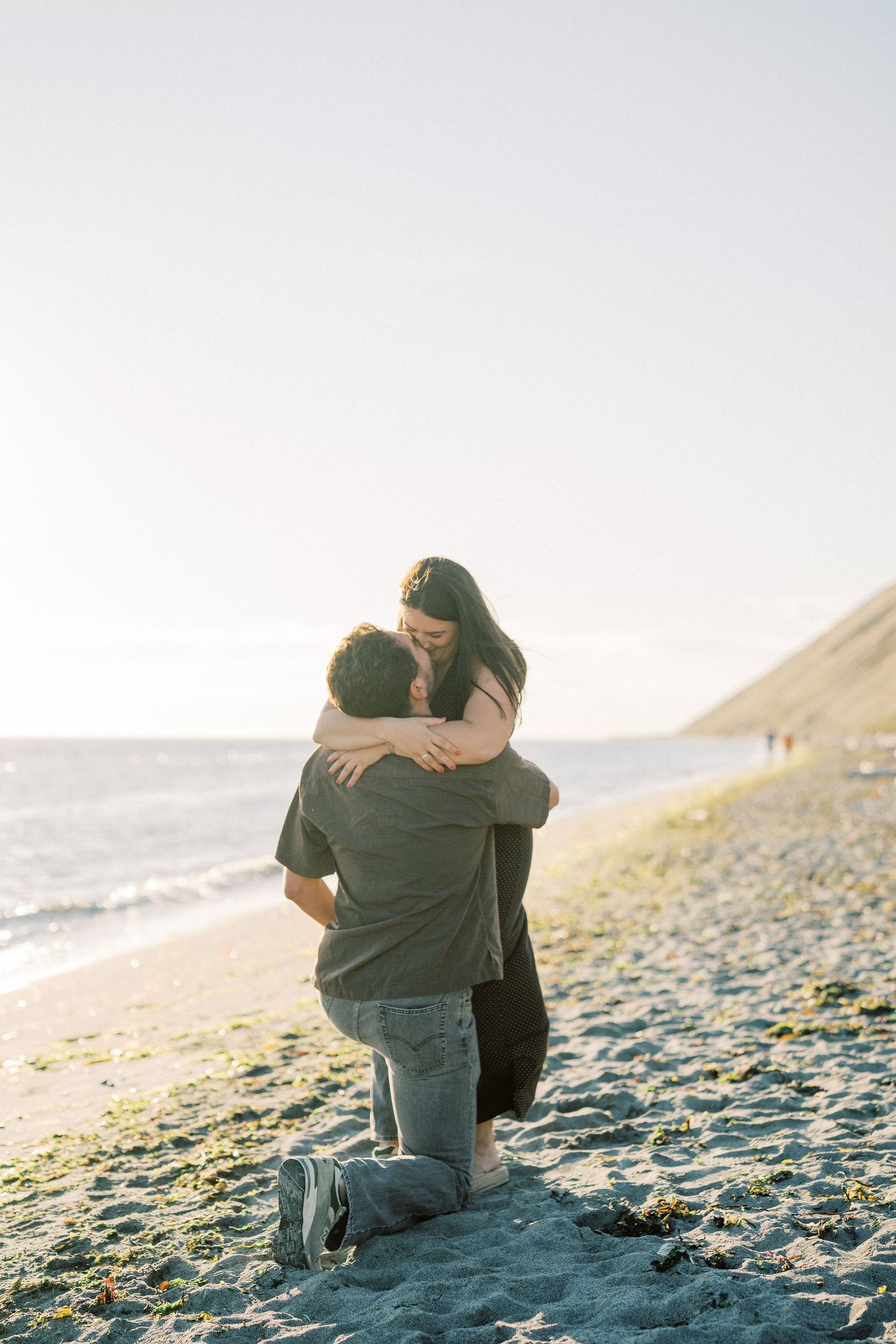 She holds him as he is still kneeling after she said yes, Whidbey Island proposal photographer, Freeland
