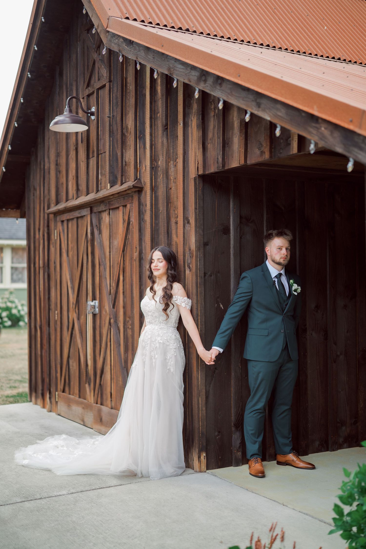 Bride and groom hold hands beside the barn doors at The Kelley Farm, Bonney Lake