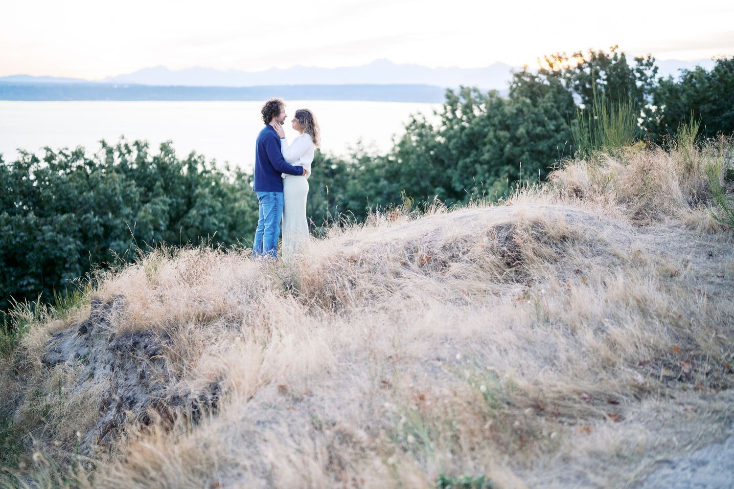 Couple on the south bluff with Puget Sound behind them, Discovery Park proposal photographer, Seattle