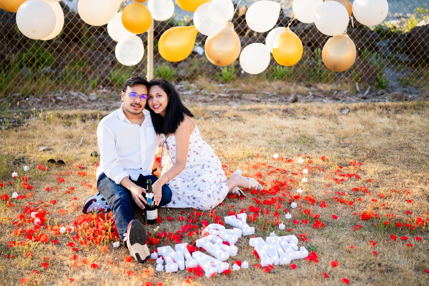 Sitting in the petals with their dog and the champagne, West Point Lighthouse proposal photographer, Seattle