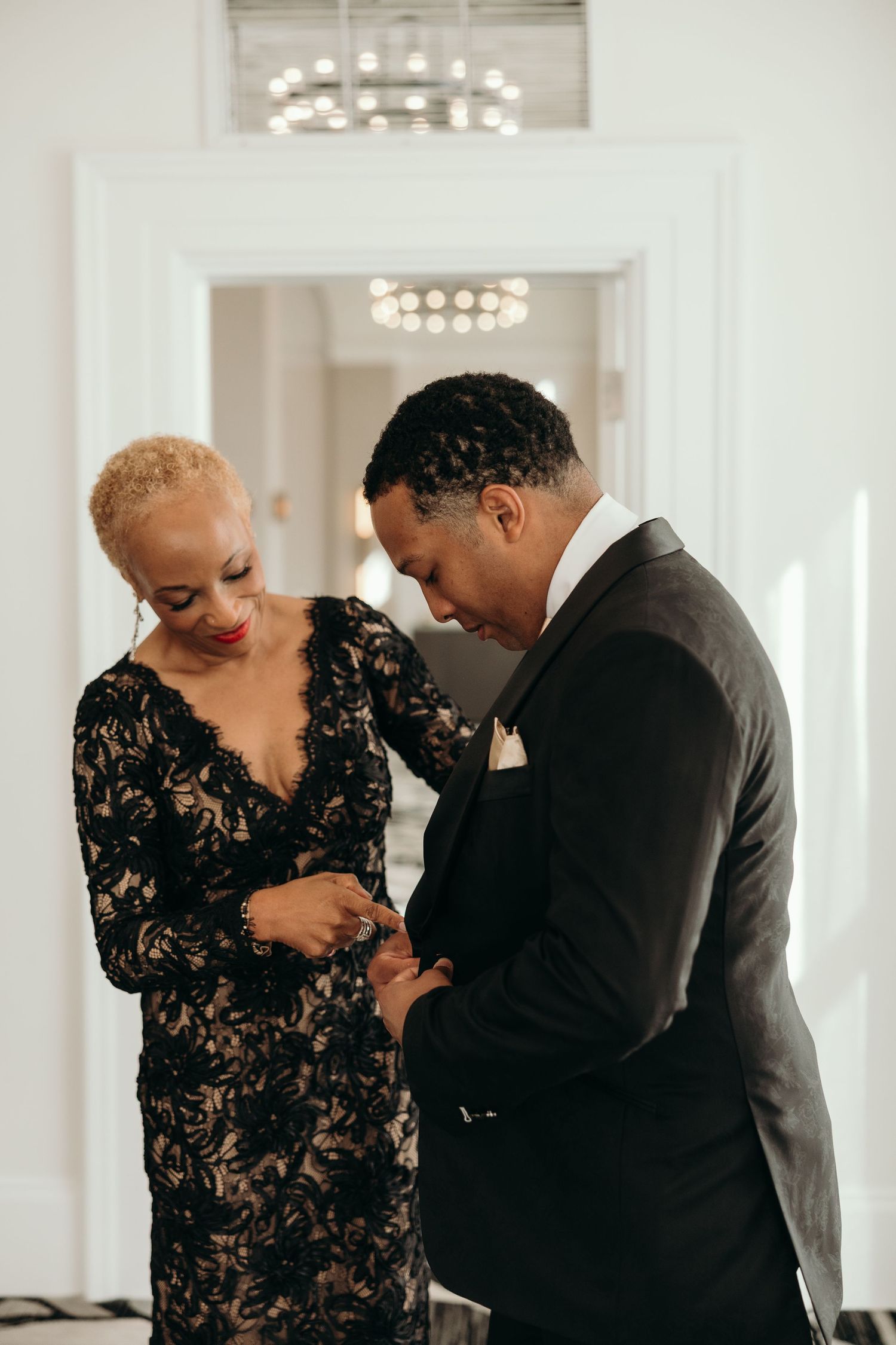 Elegant couple in formal attire share an intimate dance moment in a bright ballroom setting.