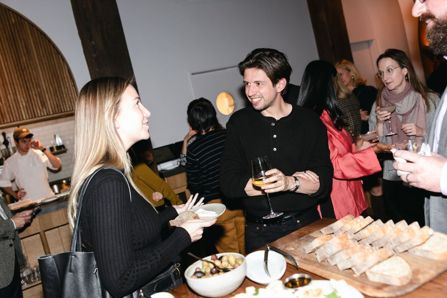 People gathered around tables enjoying food and drinks at an indoor social event.