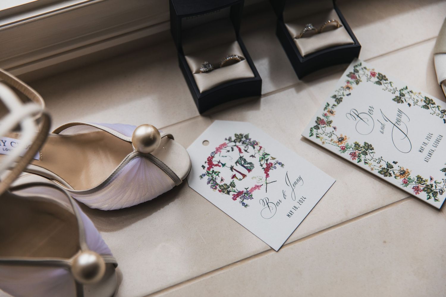 Wedding details including floral invitations and delicate accessories arranged on a light surface.