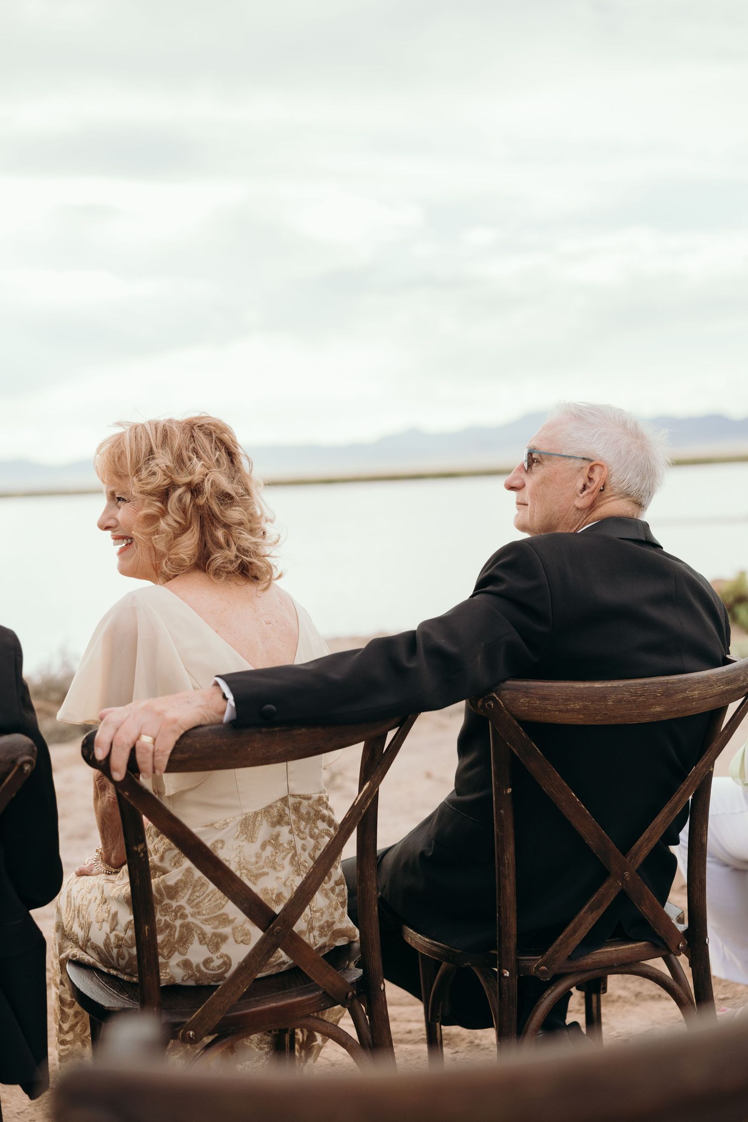 Wedding guests seated in wooden chairs overlooking a scenic desert lake view.