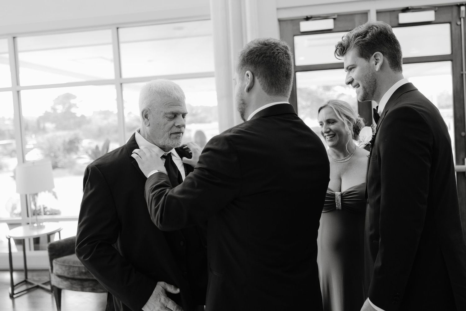 Group of men in black suits gathered at an indoor event space.