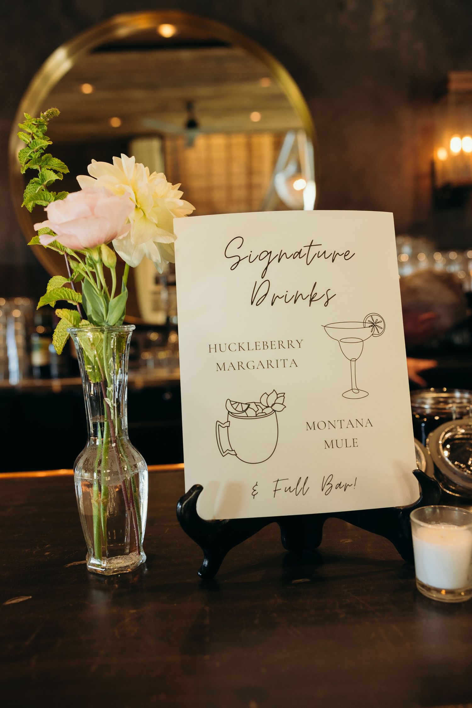 Elegant drink menu cards displayed with floral centerpieces at wedding reception.