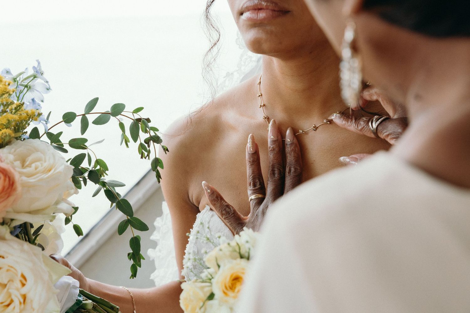 Close up details of a bridal bouquet with white and peach flowers and greenery.
