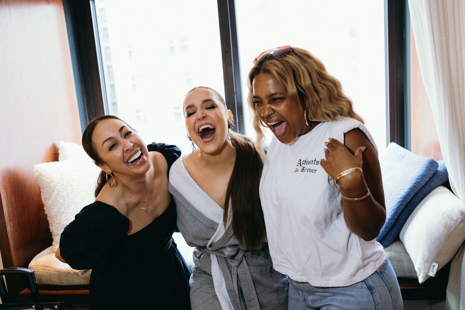 A group of people wearing white shirts laugh and smile together while posing for a casual photo.