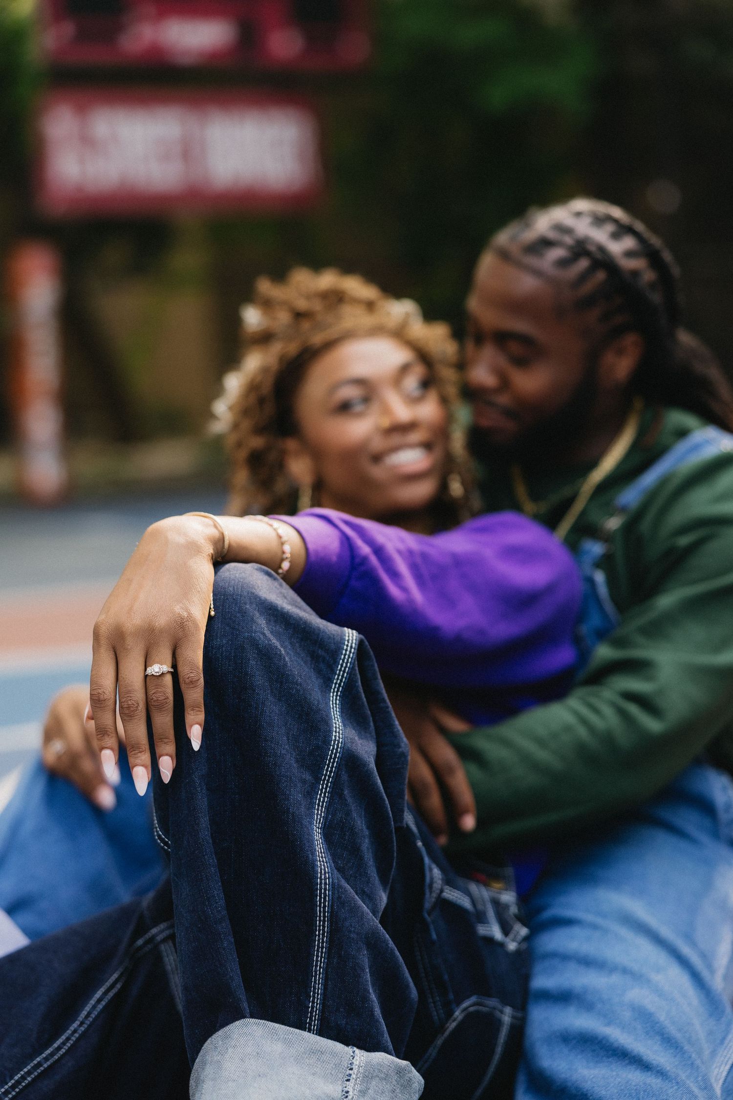 Two people in denim and casual wear embrace on an outdoor court.