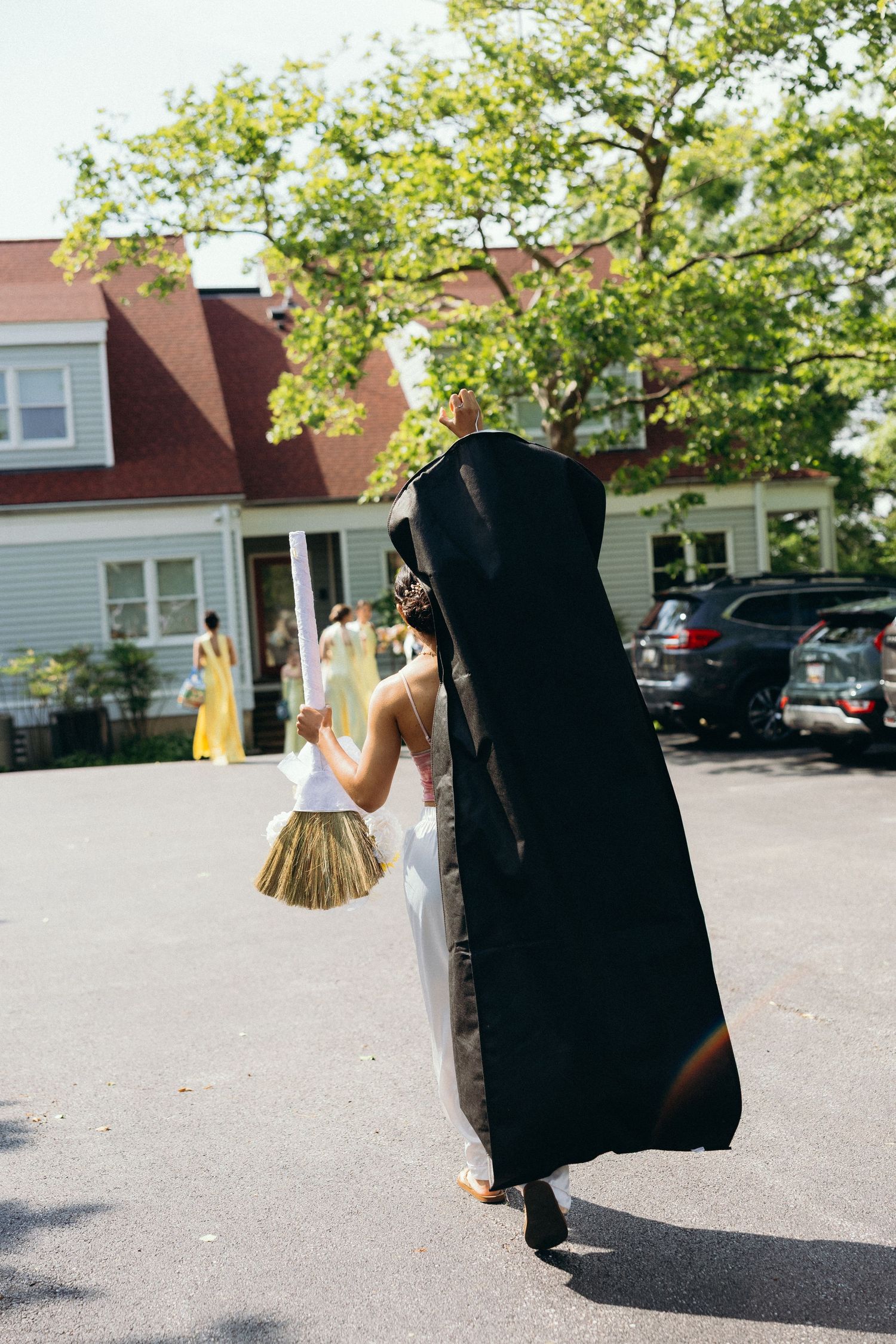 Wedding party walking through a parking lot carrying garment bags.