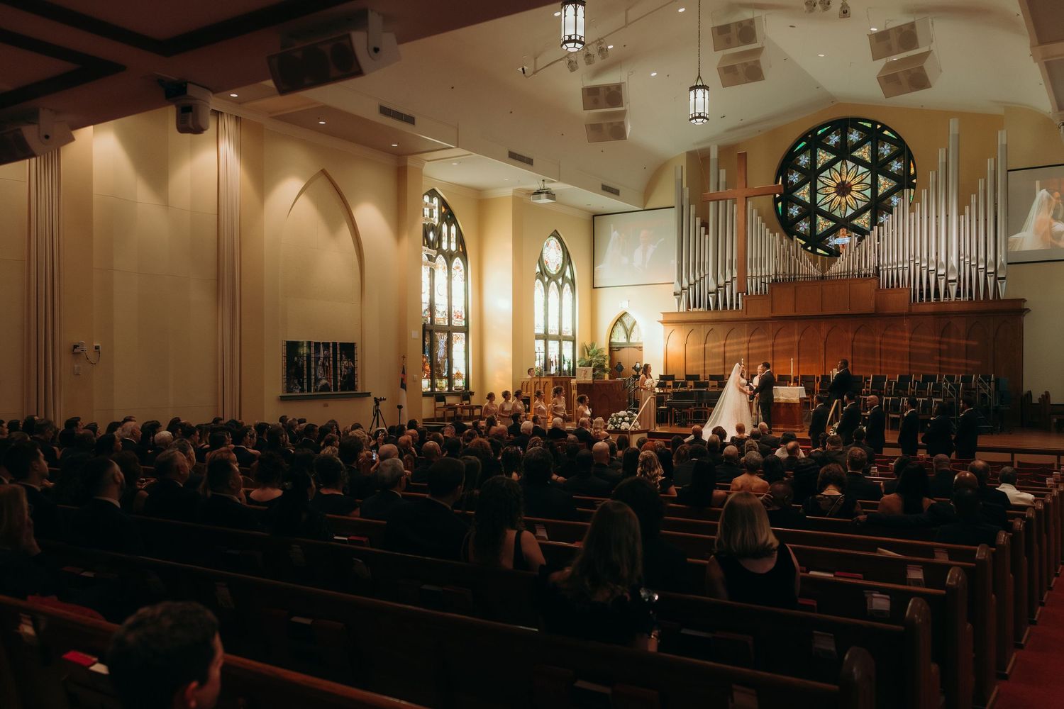 Panoramic view of a traditional church sanctuary filled with guests during a wedding ceremony.