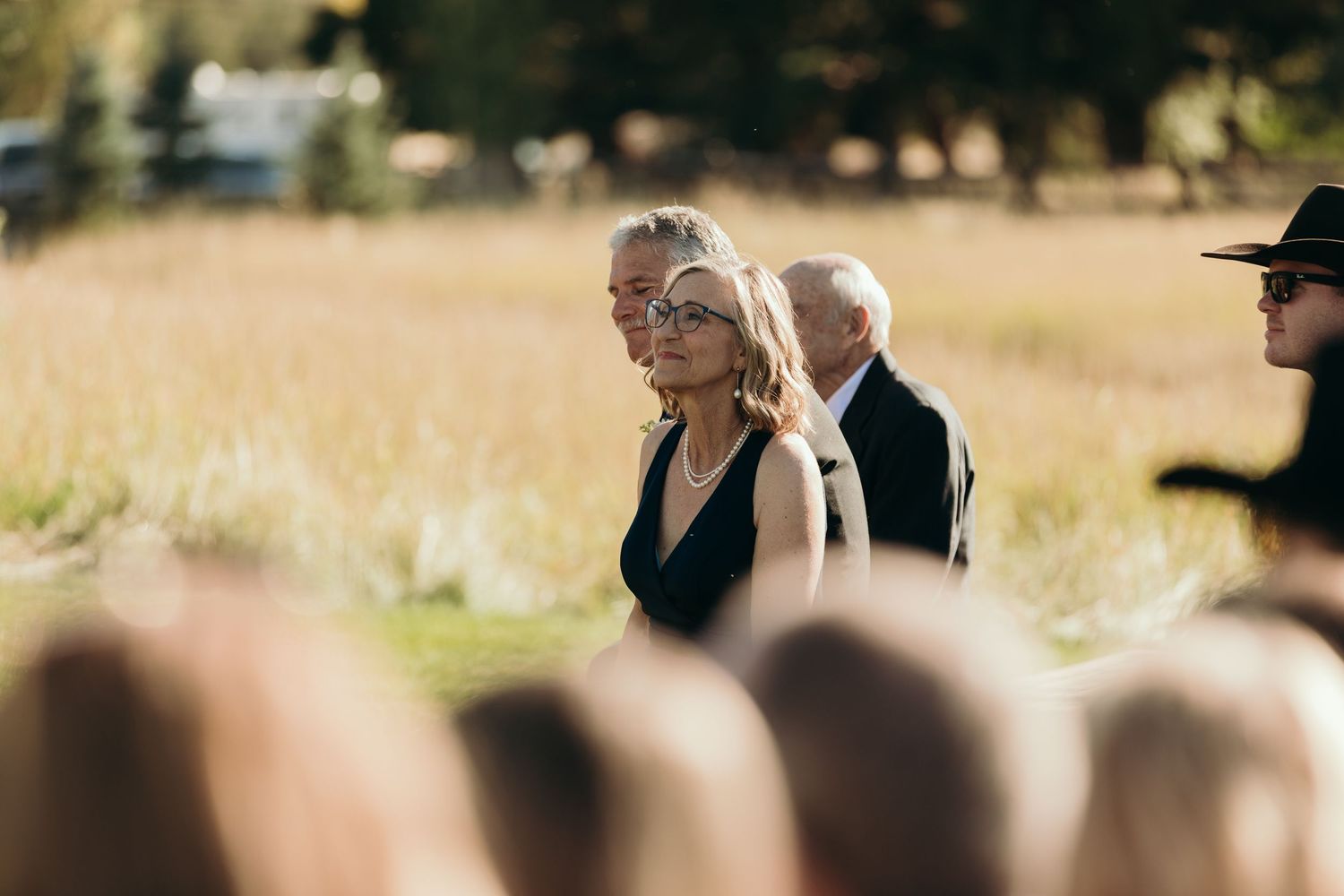 Wedding guests seated outdoors with mountain scenery in the background.