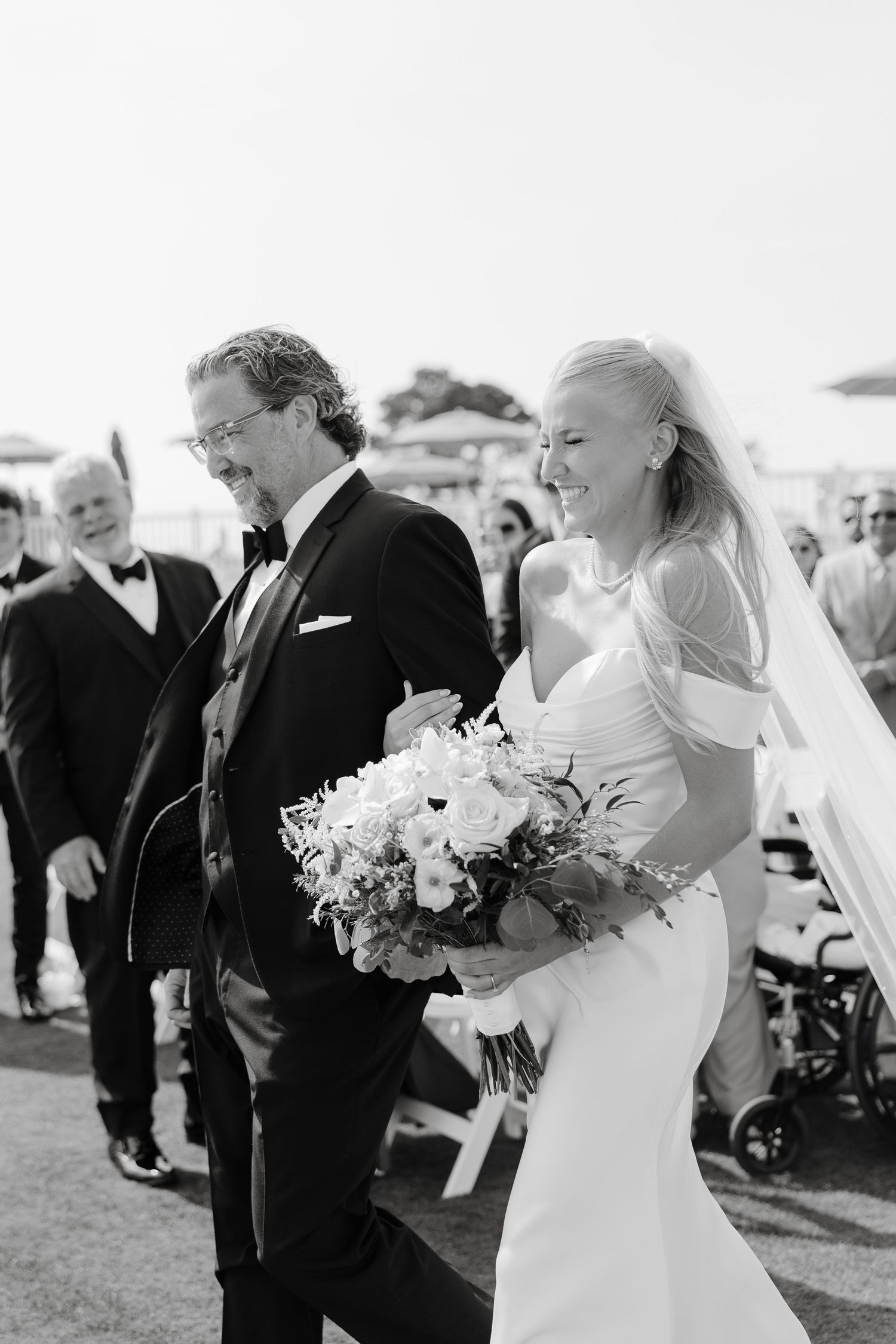 Wedding party gathering outdoors with bouquets and formal attire.