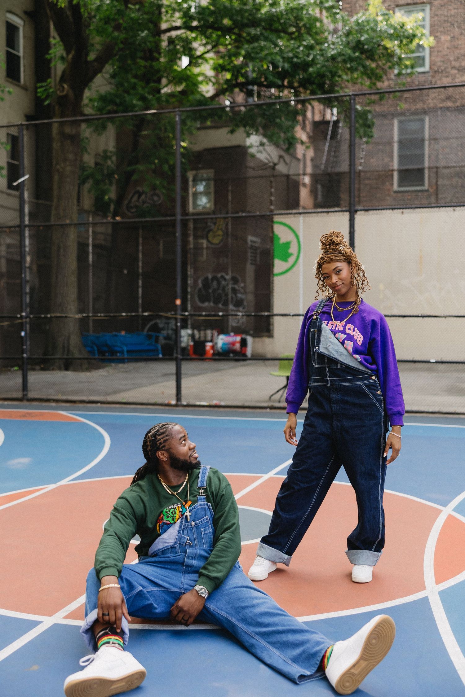Playful interaction between two people on an urban basketball court.