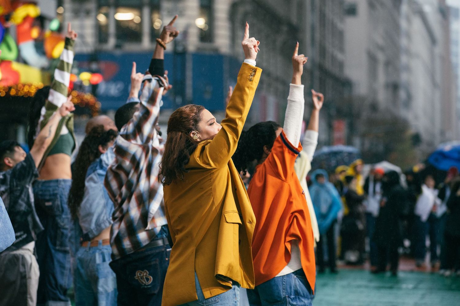 Crowd of protesters raising their arms and holding phones in an urban street at night.