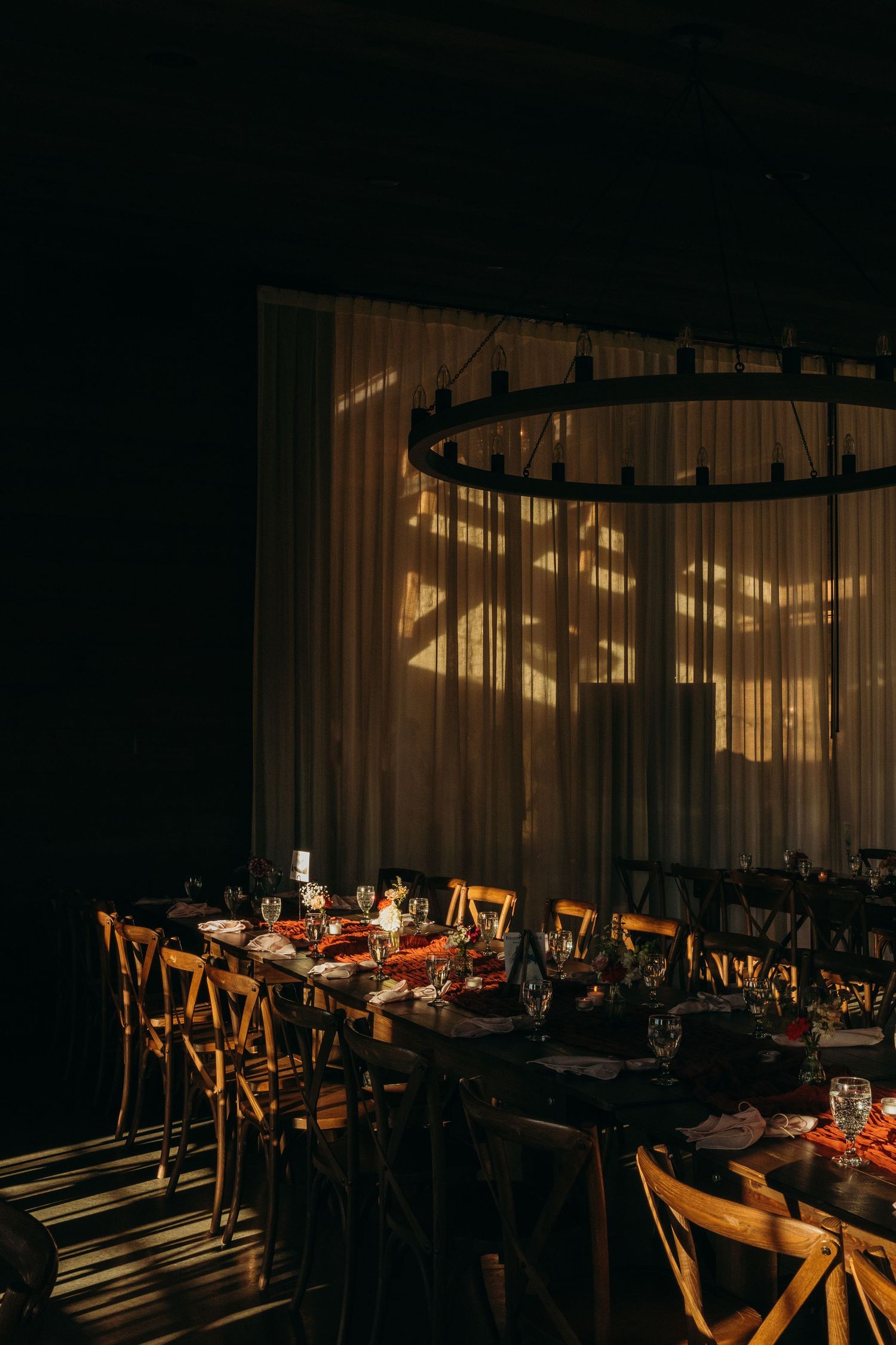 Wedding reception venue with warm lighting and wooden chairs setup for dining.