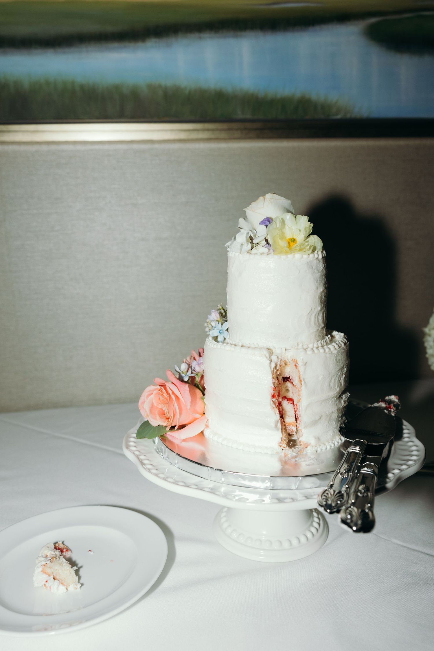 White wedding cake with delicate pink floral decorations displayed on an ornate cake stand.