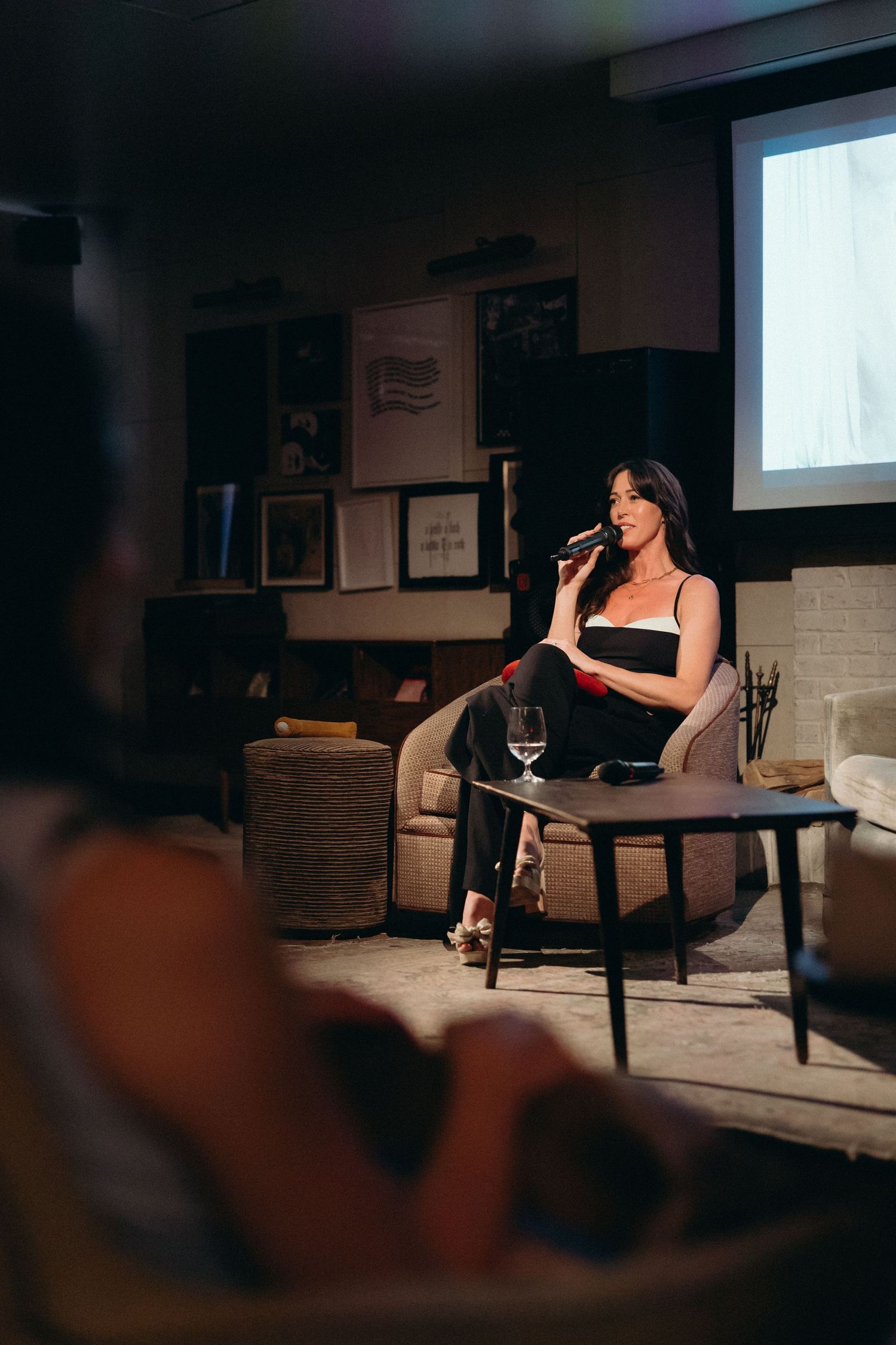A dimly lit performance space shows Lauren Rogers of Sex Ed For You at SOHO House