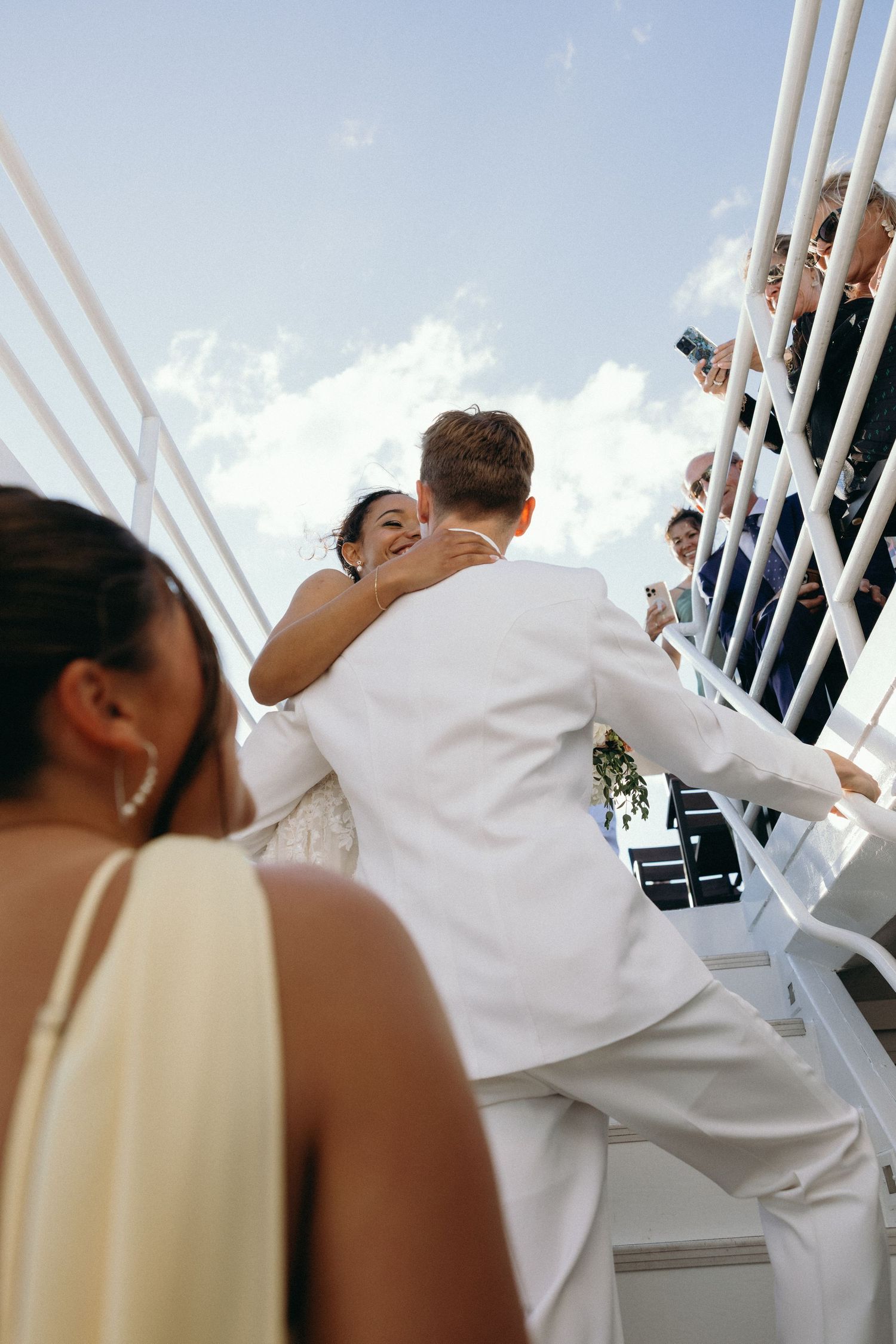 Wedding guests in white naval attire enjoying a boat celebration.