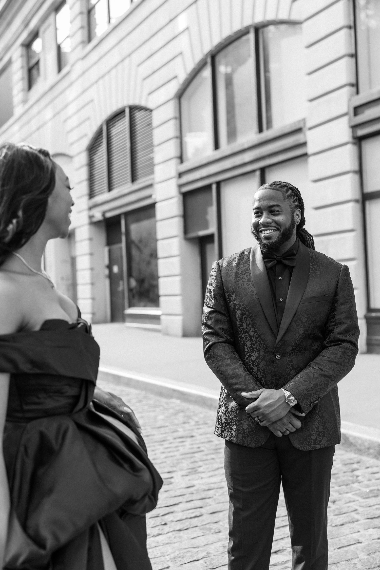 Candid black and white photos of couple laughing together on cobblestone street.