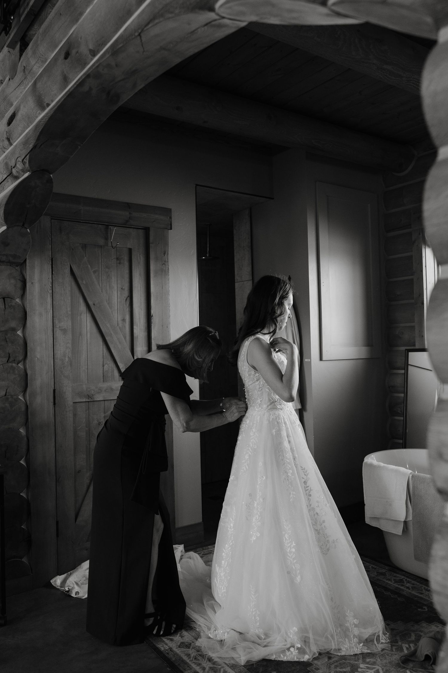 Wedding dress hangs in a dimly lit rustic cabin interior.