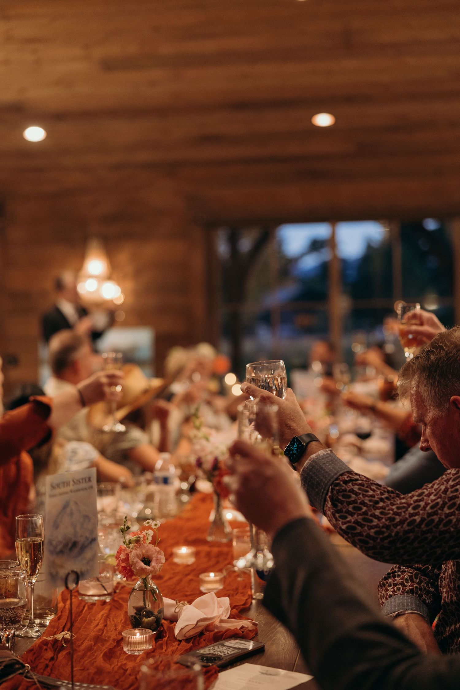 Wedding reception dinner scene with warm ambient lighting and rustic wooden interior.