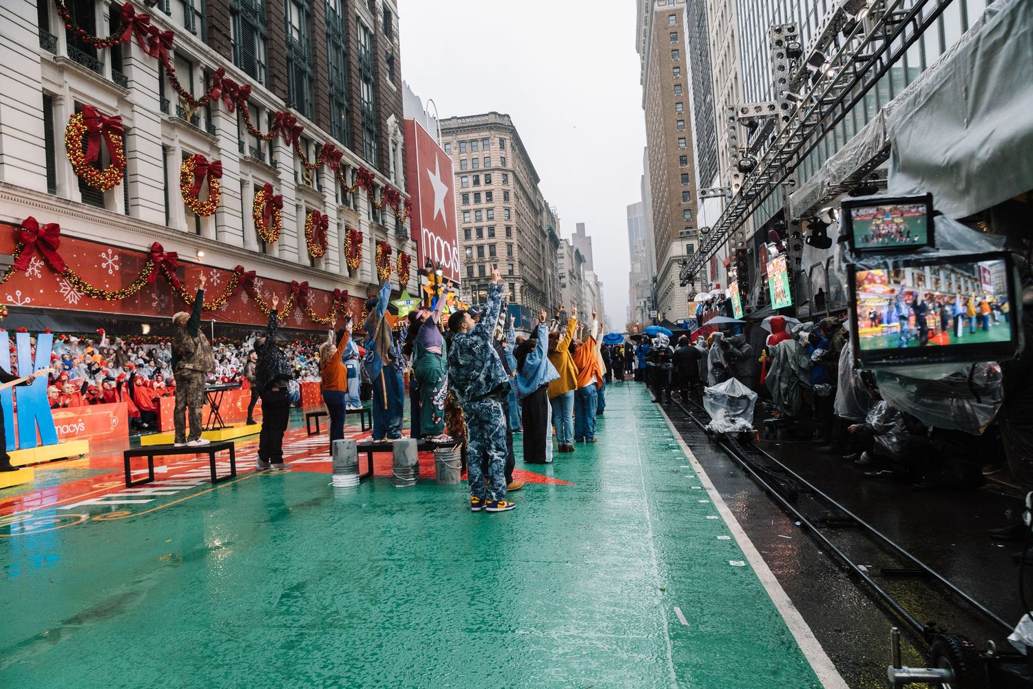 Wet urban street scene with green pavement and buildings lining both sides.