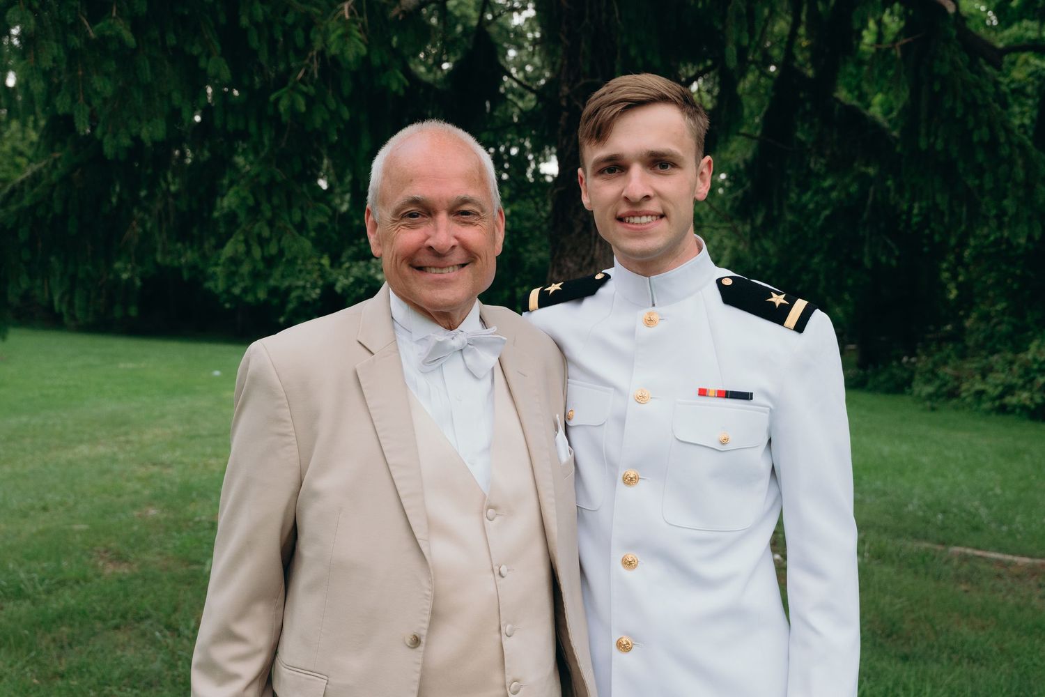 Men in formal attire posing outdoors at a wedding event.